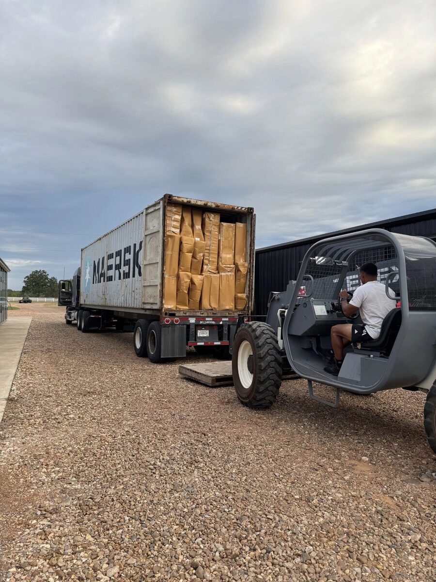 PRO MOVE crew unloading a container of wrapped inventory into storage with a telehandler
